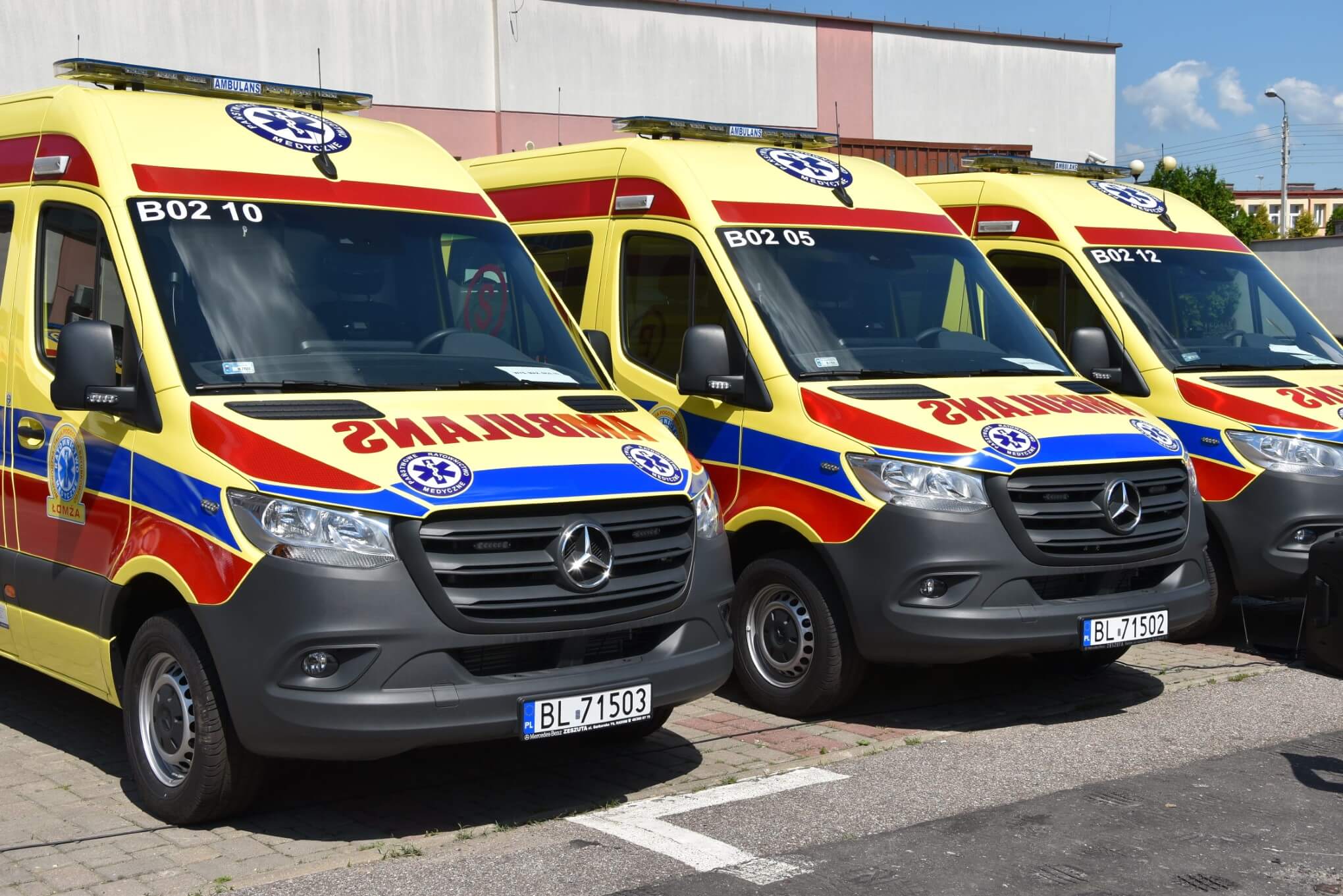 Trzy nowe ambulanse stoją obok siebie na parkingu przed stacją Pogotowia