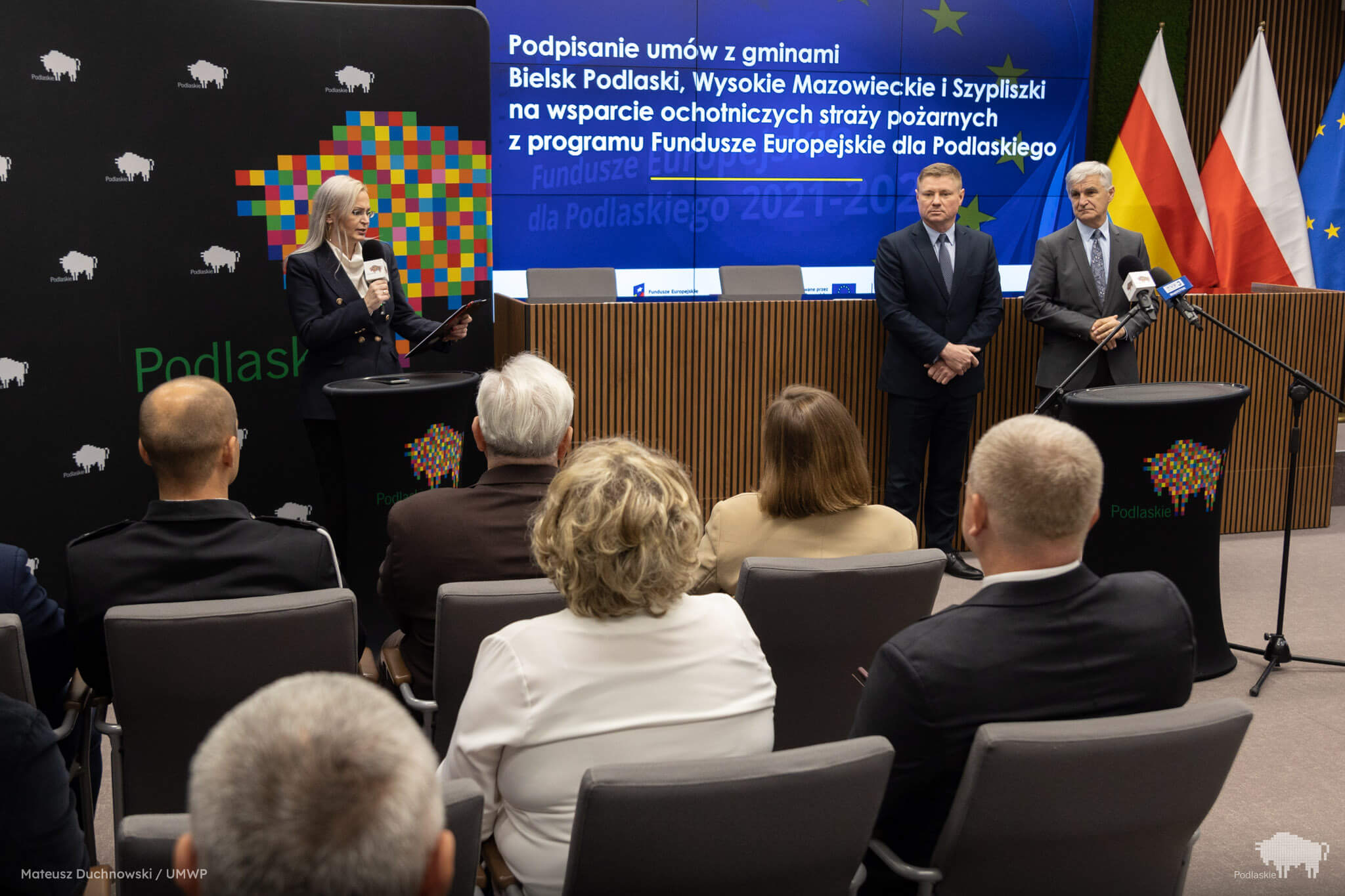 Pani w czarnej marynarce rozpoczyna konferencję.zyna konferemck