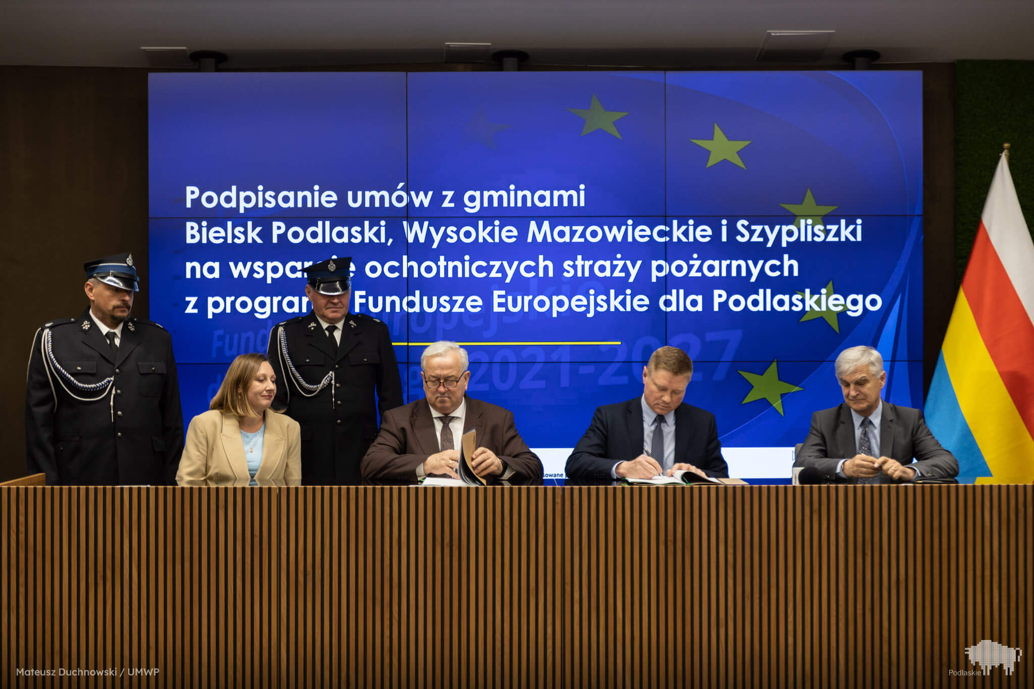 Grupa osób podpisuje dokument.