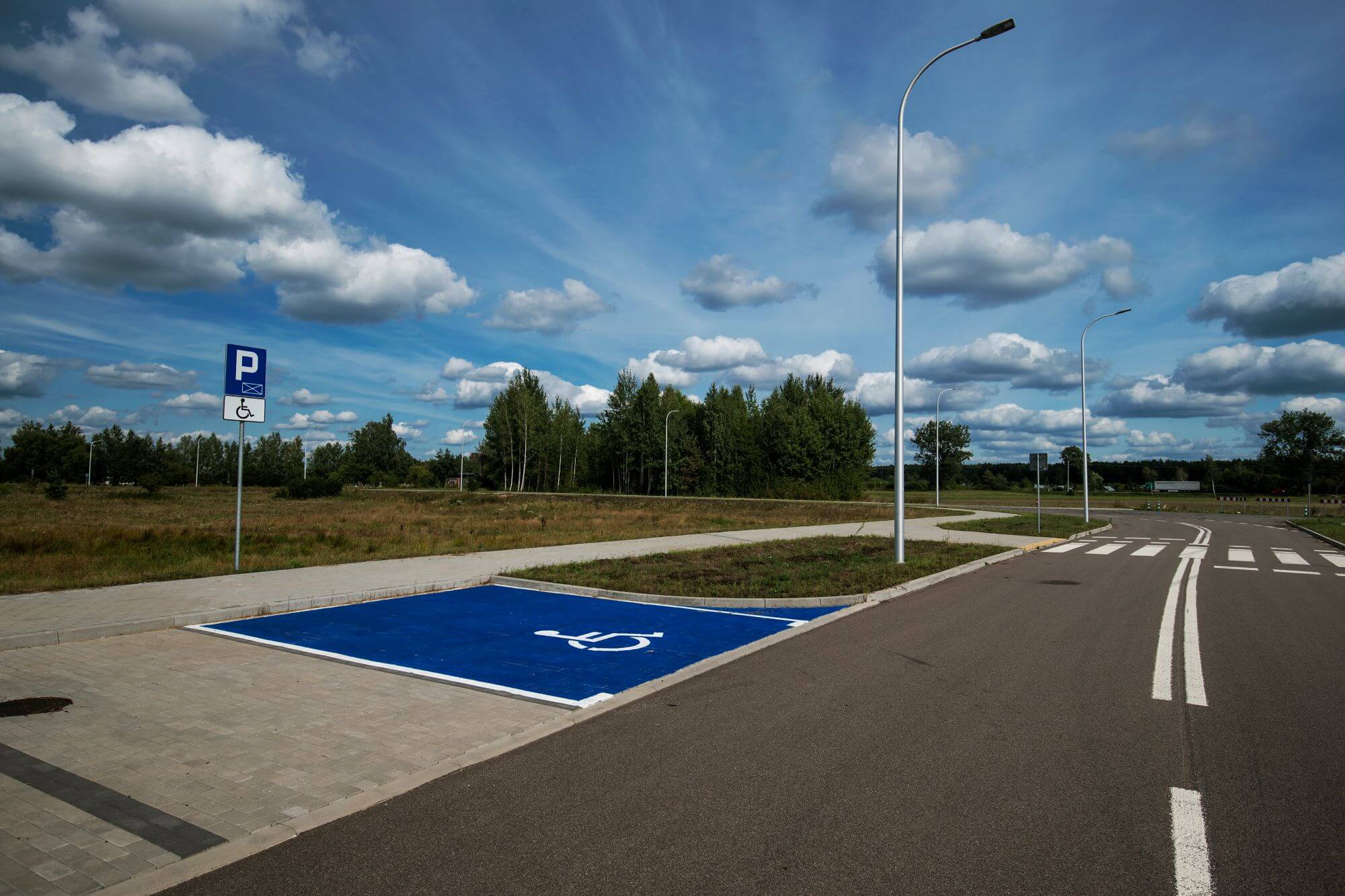 Ulica przy terenach inwestycyjnych. Oznakowane miejsce parkingowe dla osoby niepełnosprawnej