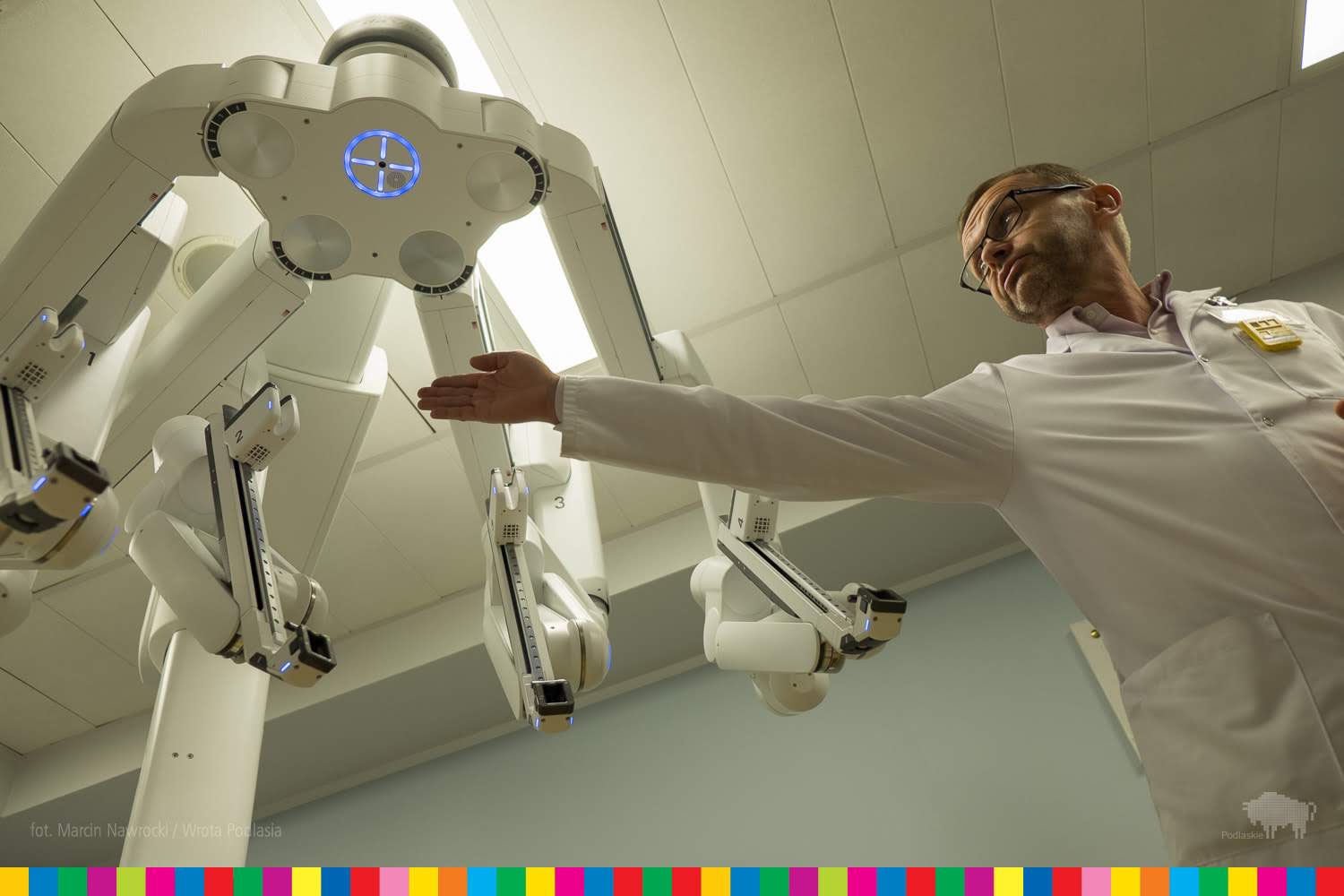 Mężczyzna wskazuje na element robota chirurgicznego