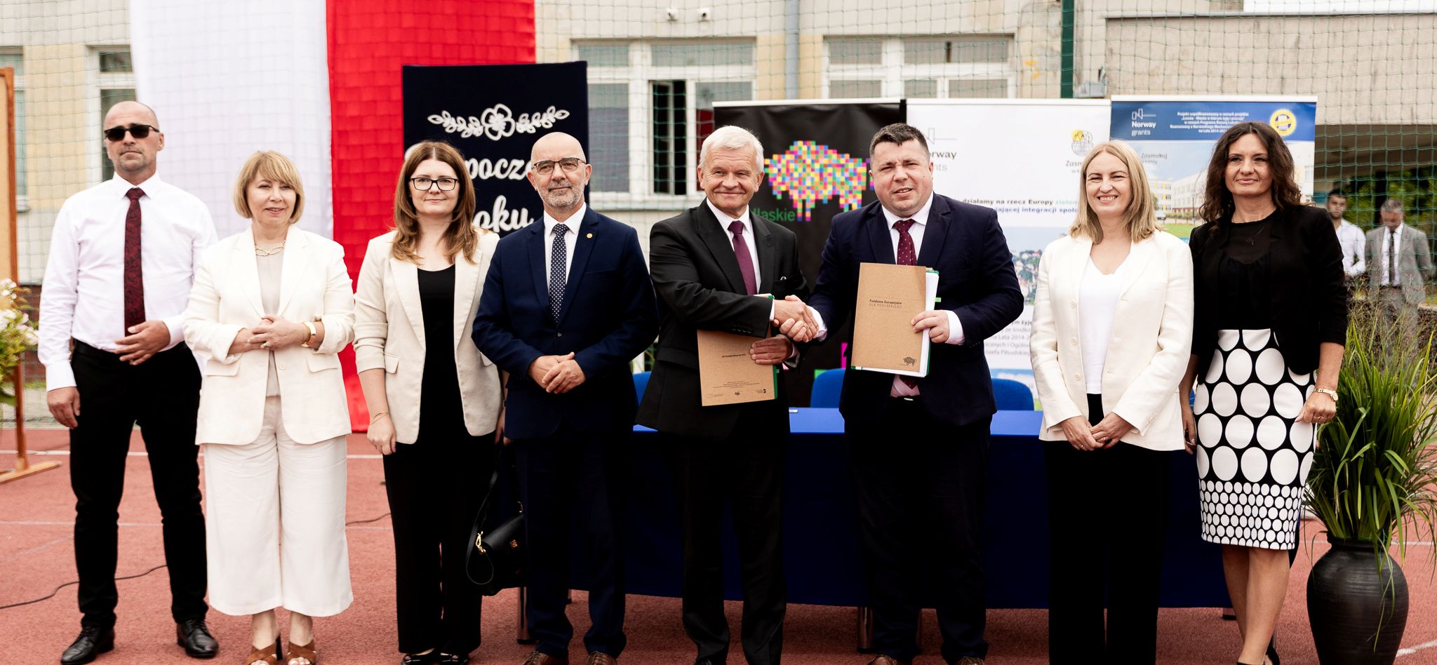 Grupa osób pozuje do pamiątkowego zdjęcia.