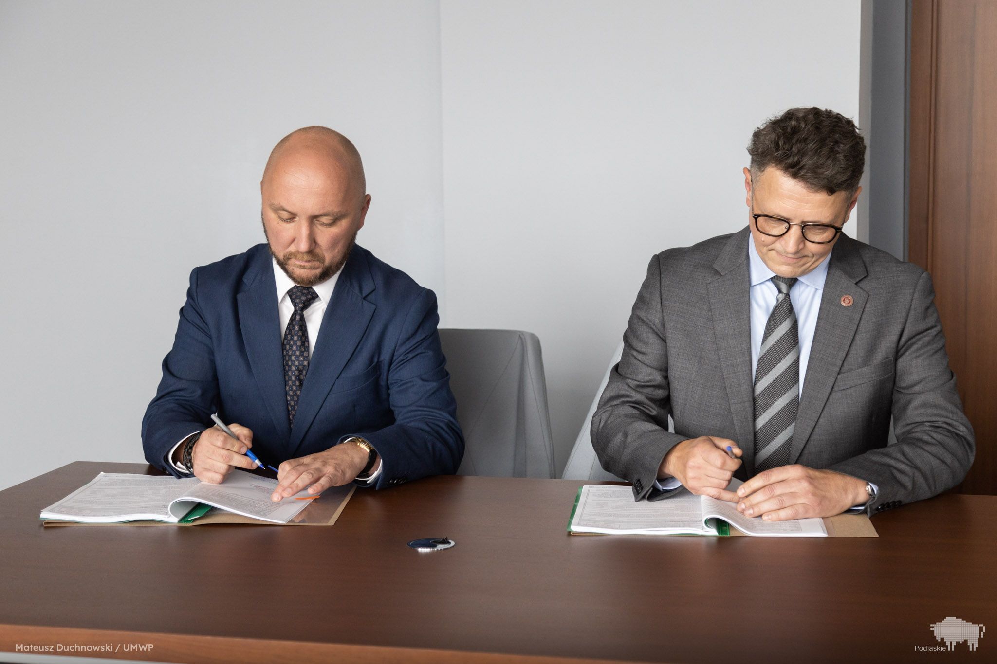 Grupa osób podpisuje dokument.