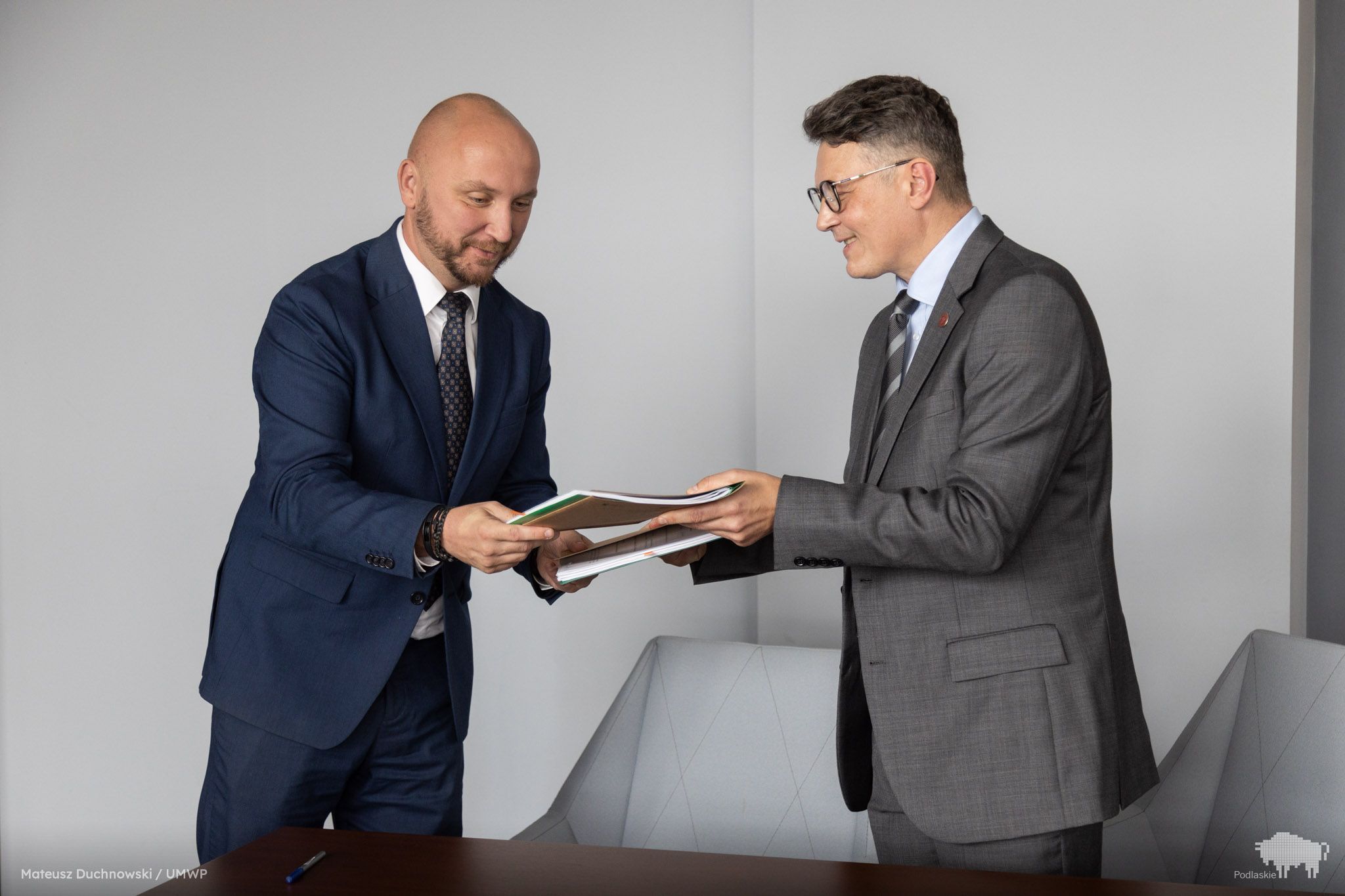 Grupa osób przekazuje podpisany dokument.