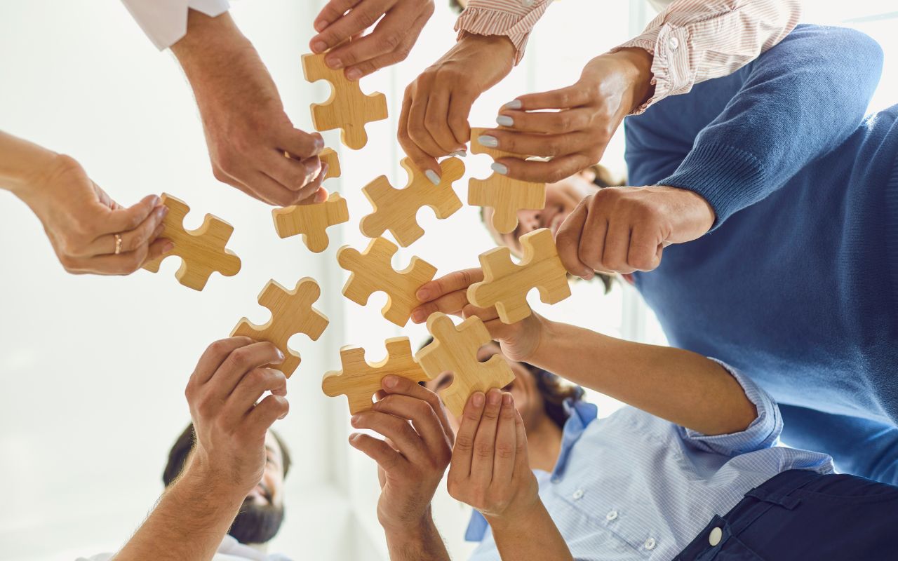 Kilka rąk trzymających puzzle