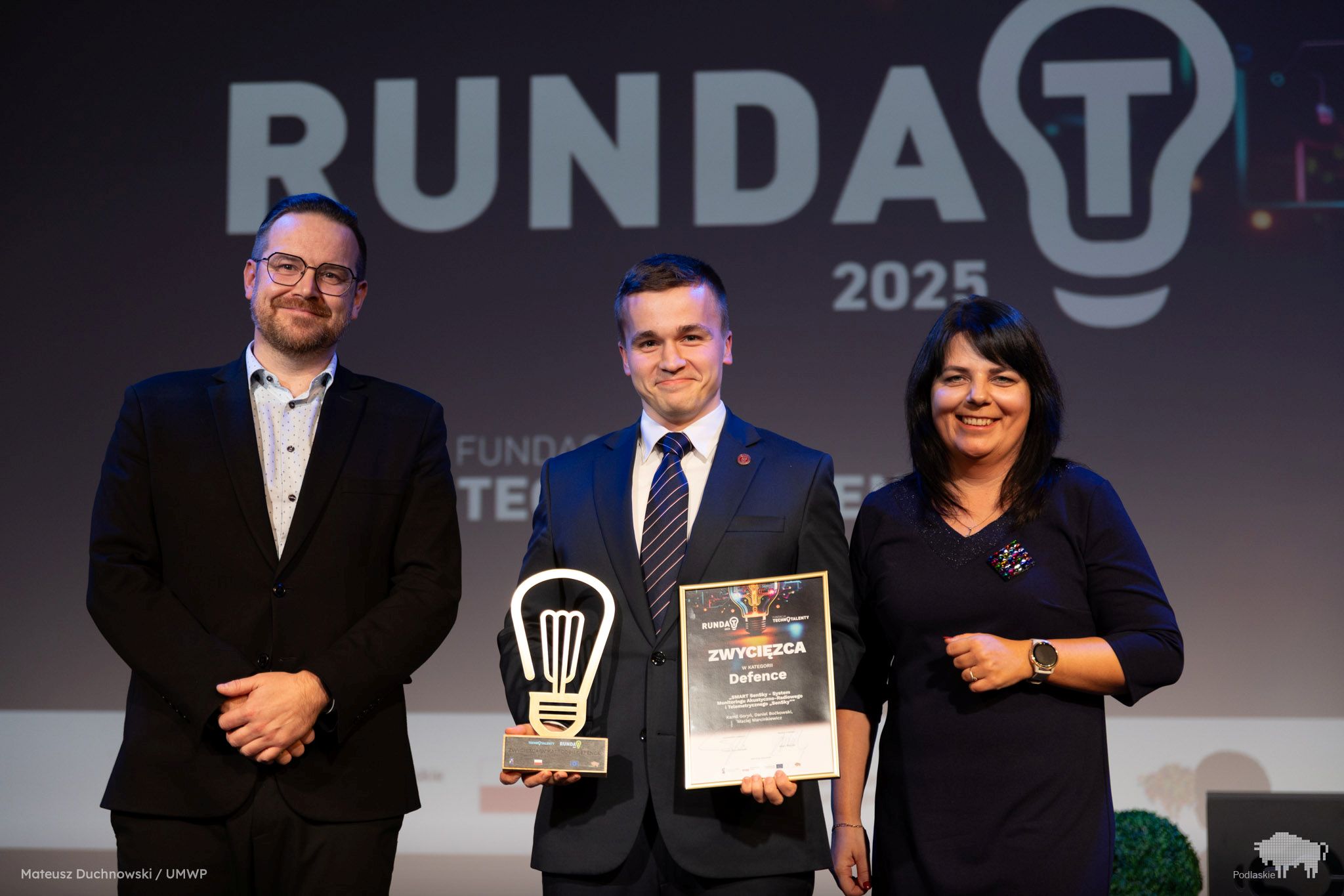 Laureat pozuje do zdjęcia ze statuetką.