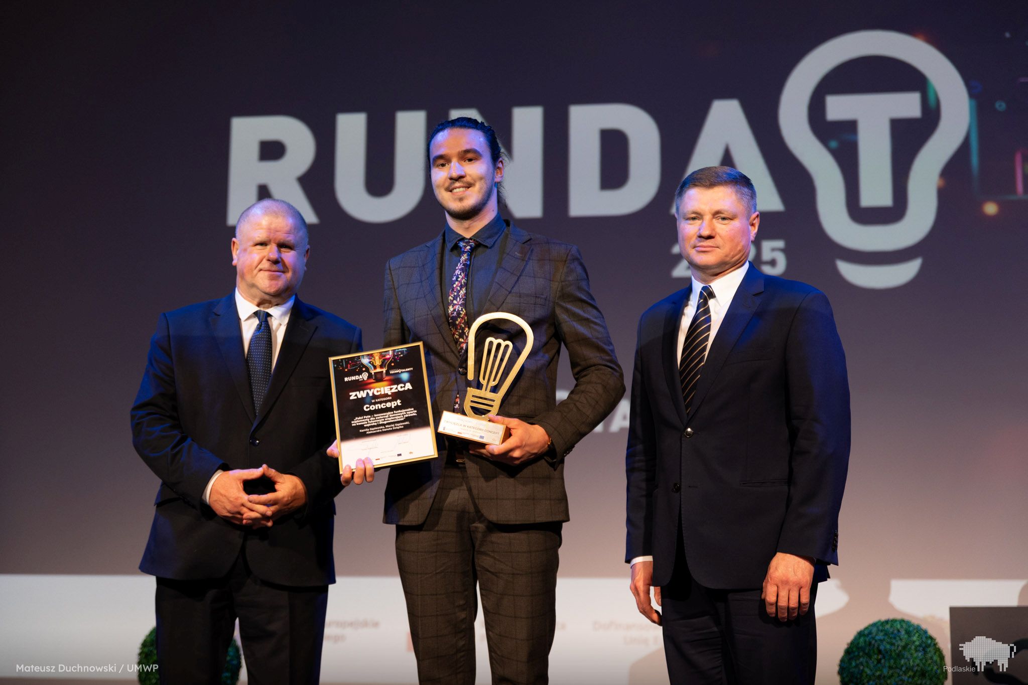 Laureat pozuje do zdjęcia ze statuetką.