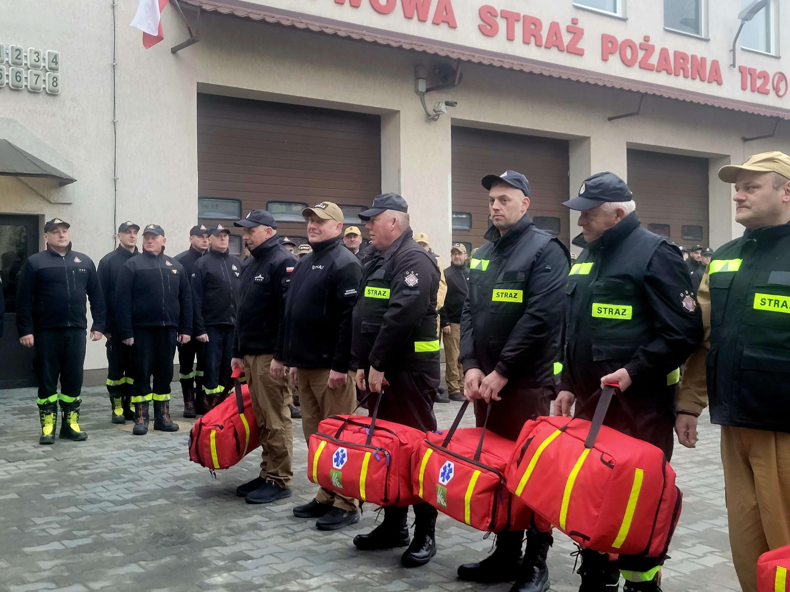 Strażacy stoją w rzędzie obok siebie podczas uroczystości