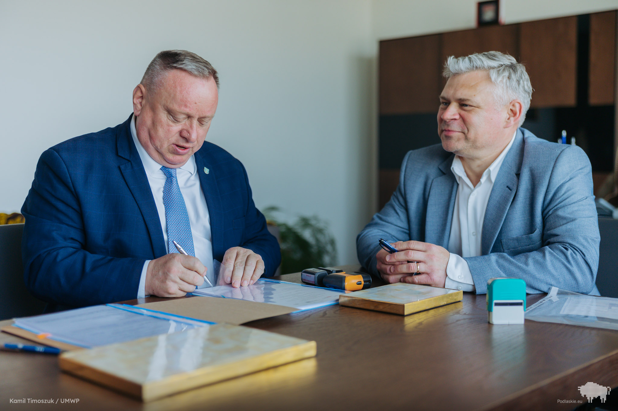 Grupa osób podpisuje dokument.