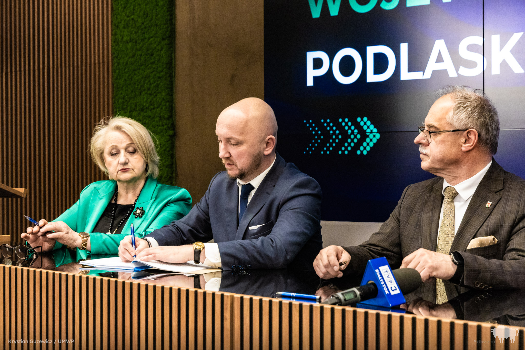 Grupa osób podpisuje dokument.