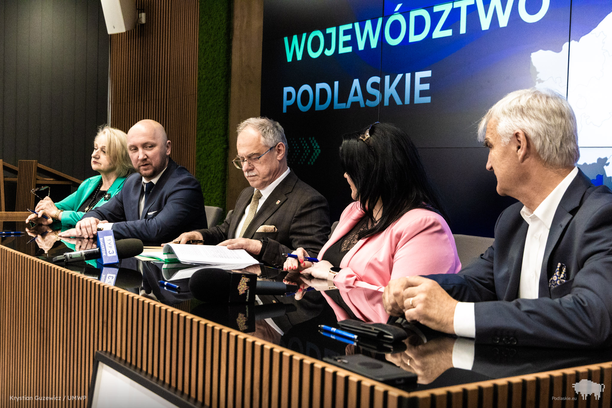 Grupa osób podpisuje dokument.
