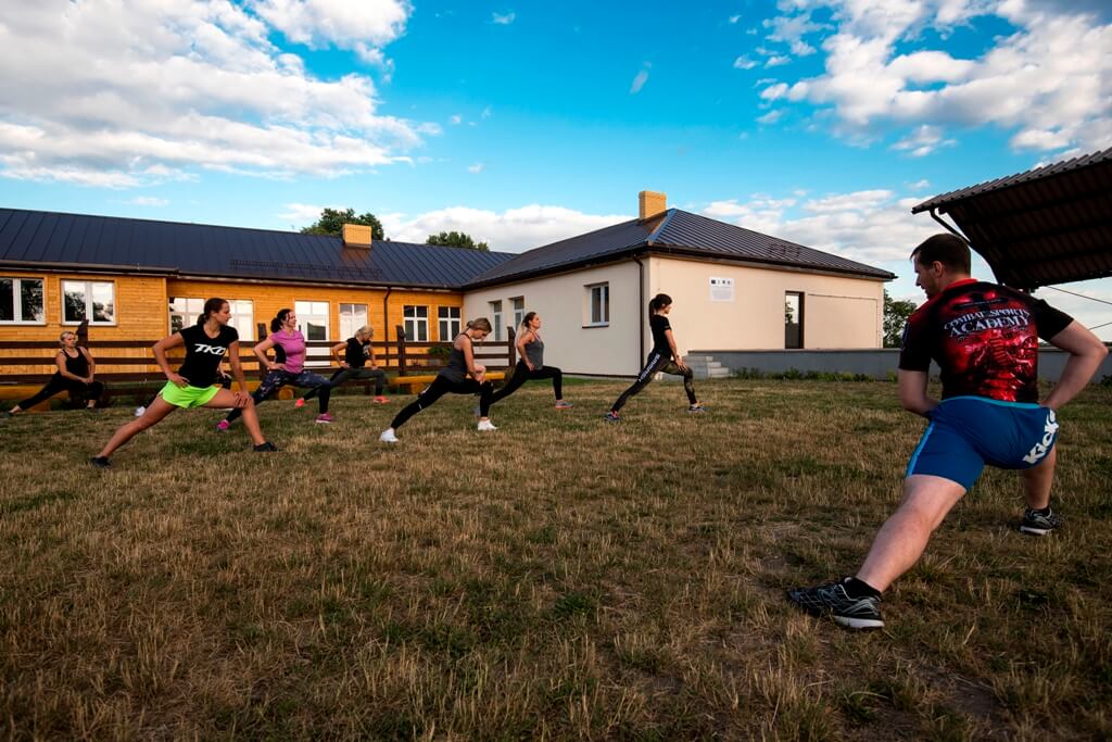 Uczestnicy zajęć fitness ćwiczą przed budynkiem centrum