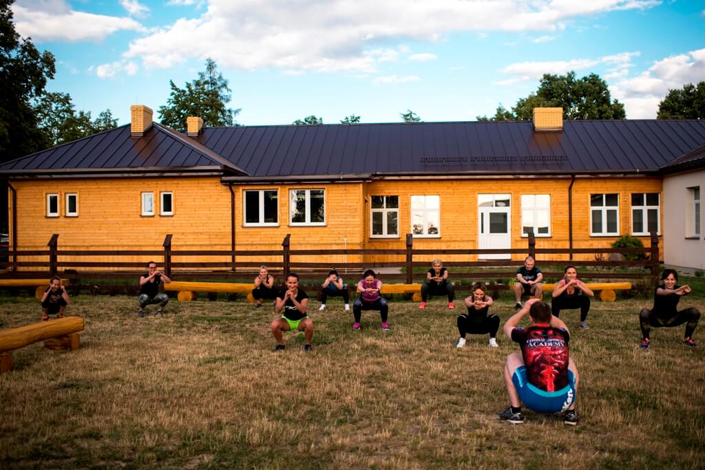 Uczestnicy zajęć fitness ćwiczą przed budynkiem centrum
