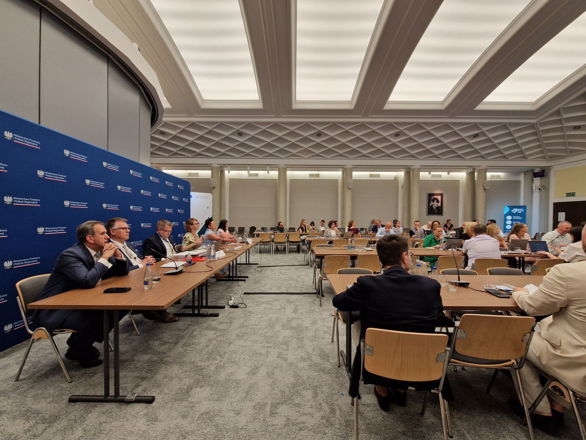 Duża grupa siedzi przy stołach podczas konferencji