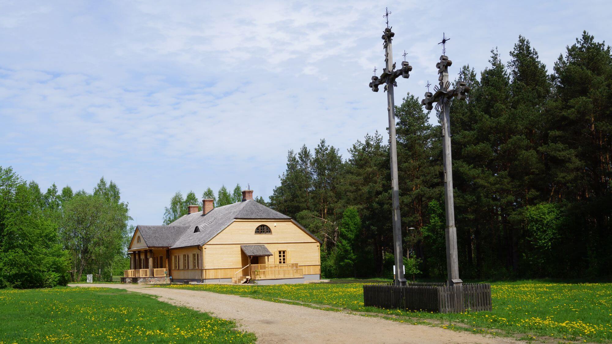 Zabytkowy drewniany dwór stoi przy piaszczystej drodze