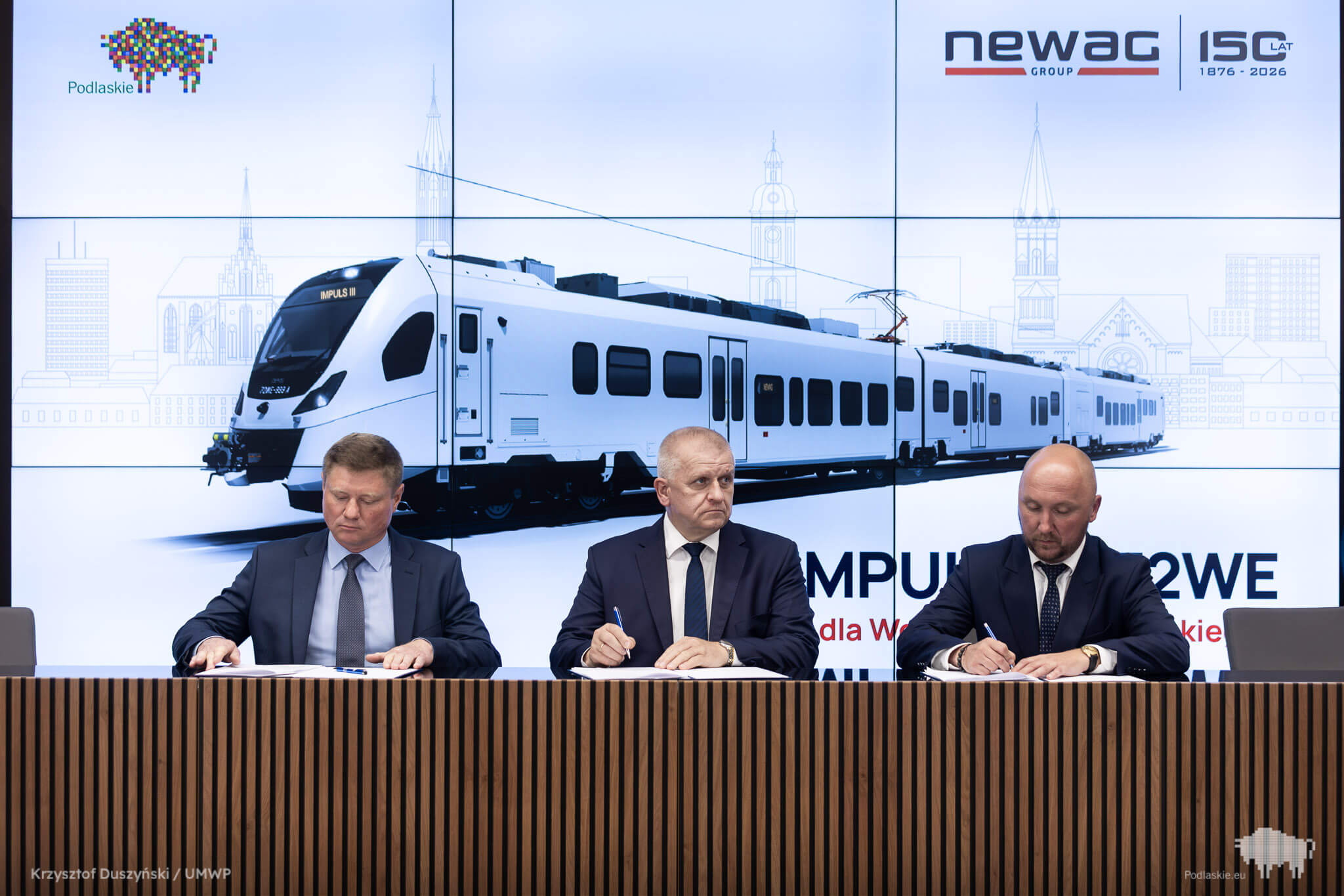 Trzech mężczyzn podpisuje umowę