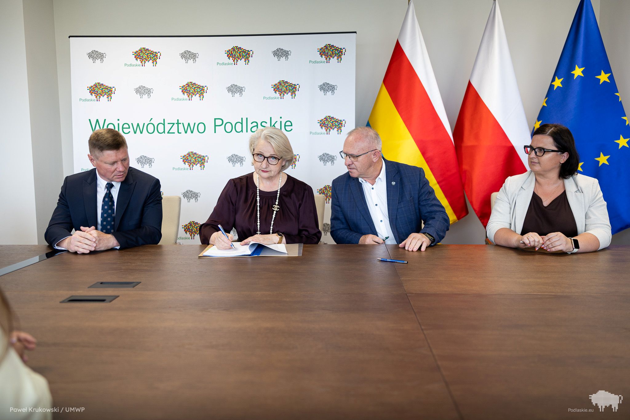 Grupa osób podpisuje dokument.