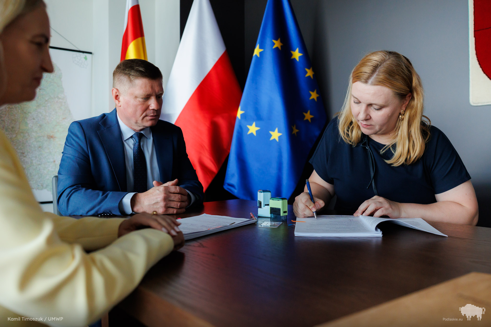 Grupa osób podpisuje dokument.