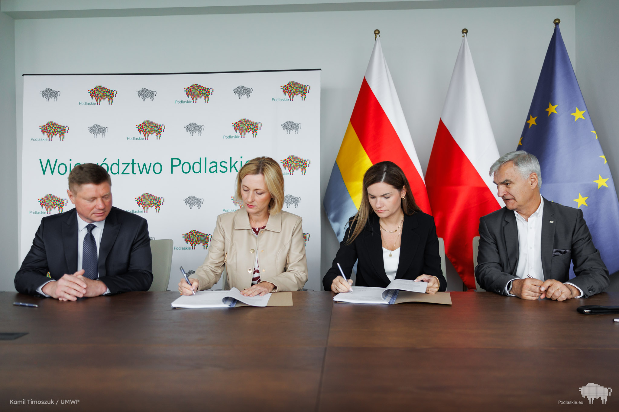 Grupa osób podpisuje dokument.