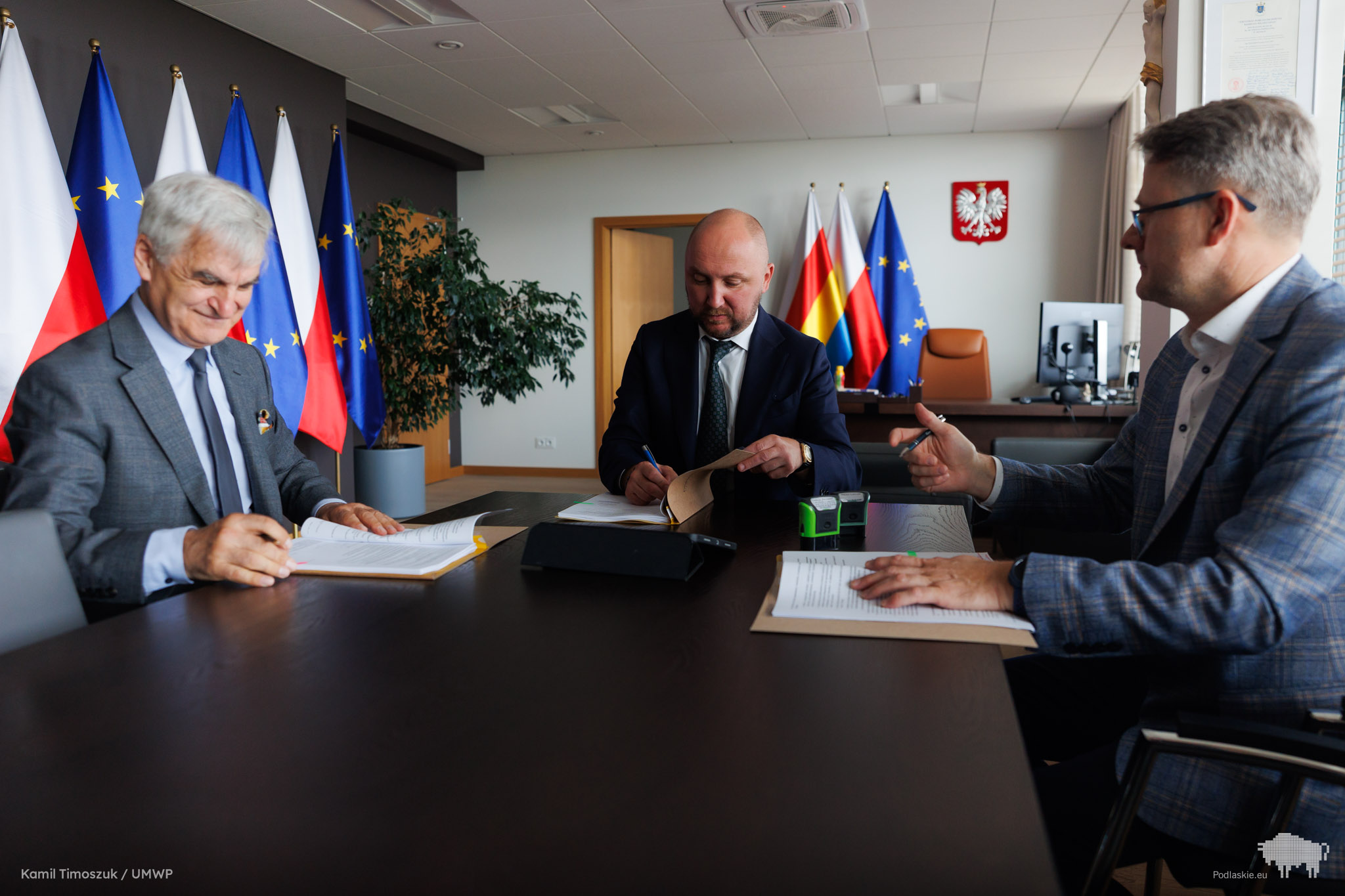 Grupa osób podpisuje dokument.