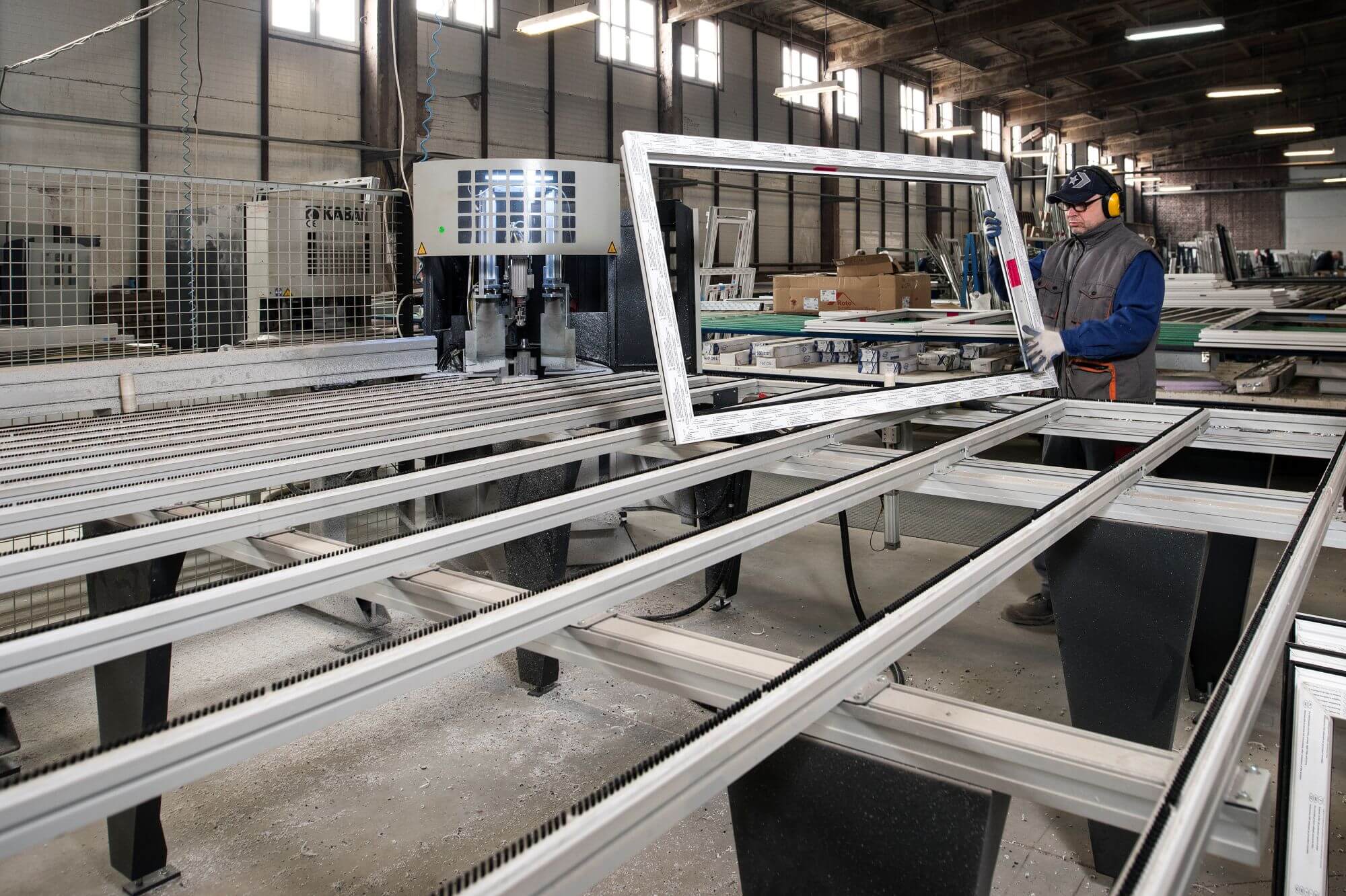Pracownik firmy Atlant w hali produkcyjnej przygotowuje ramę okienną