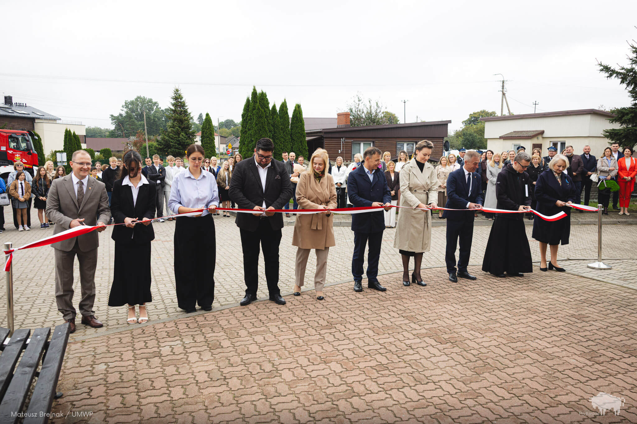 Kilka osób przecina biało-czerwoną wstęgę
