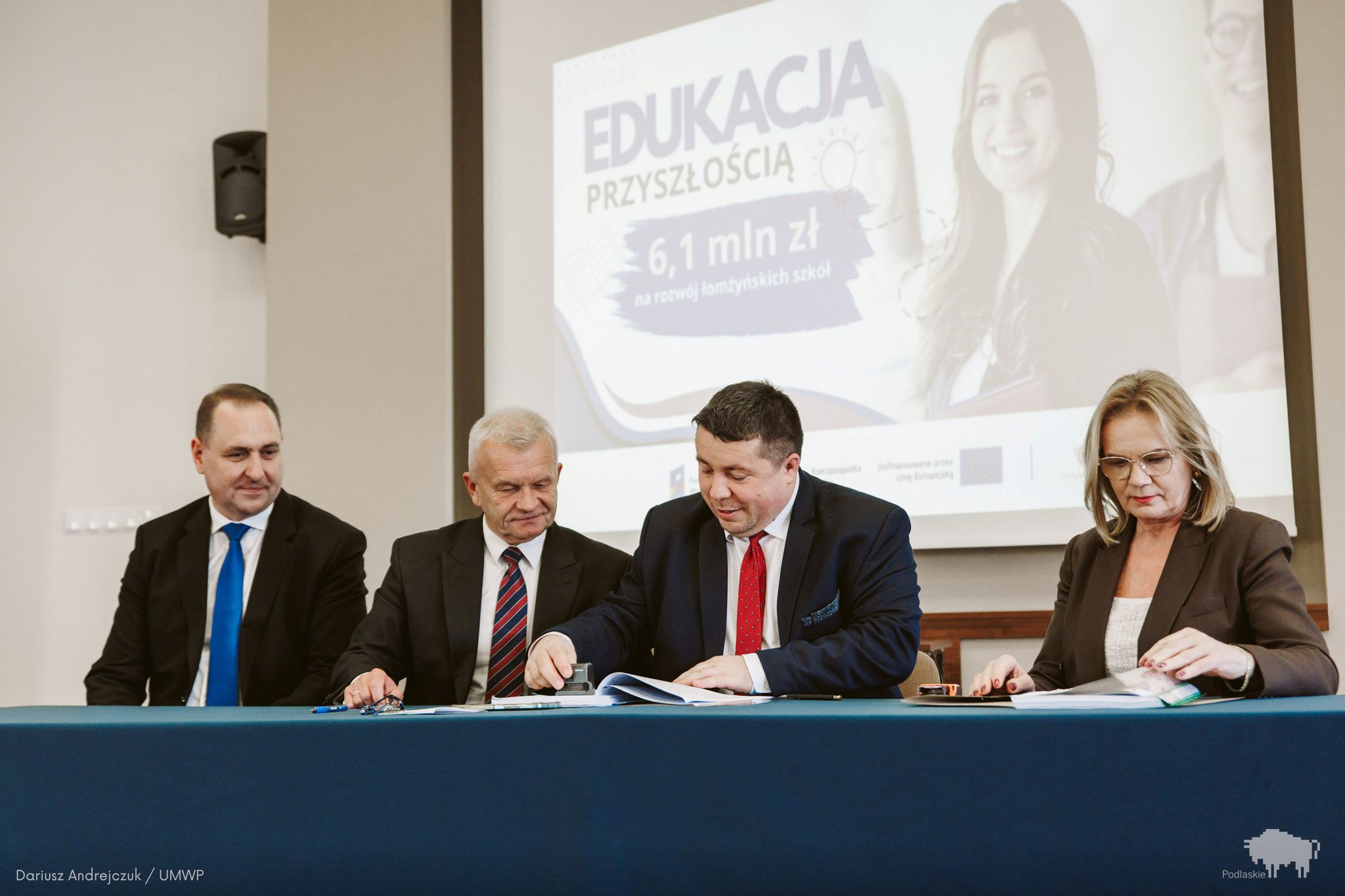 Grupa osób podpisuje dokument.