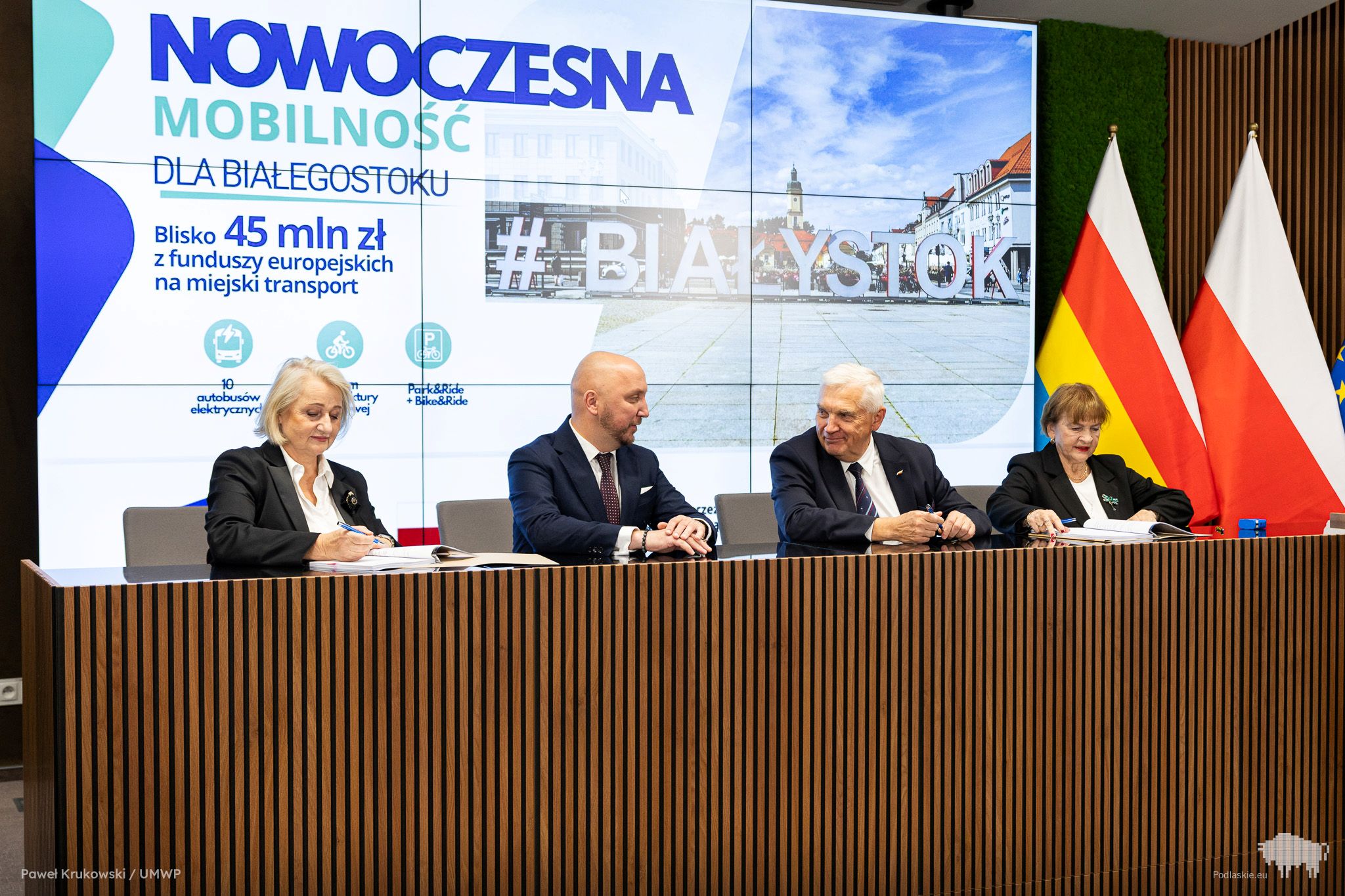 Grupa osób podpisuje dokument.