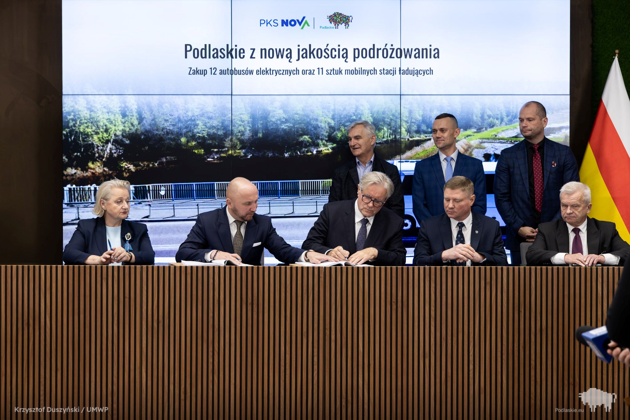 Grupa osób podpisuje dokument.